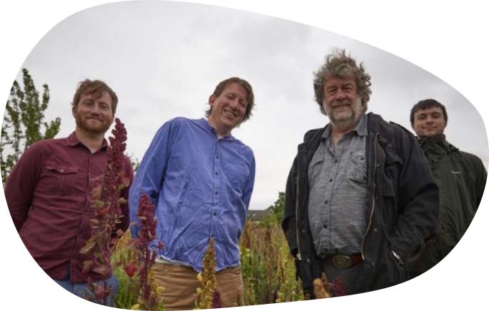 A photo of four members of Hodmedod in a wild-flower meadow.