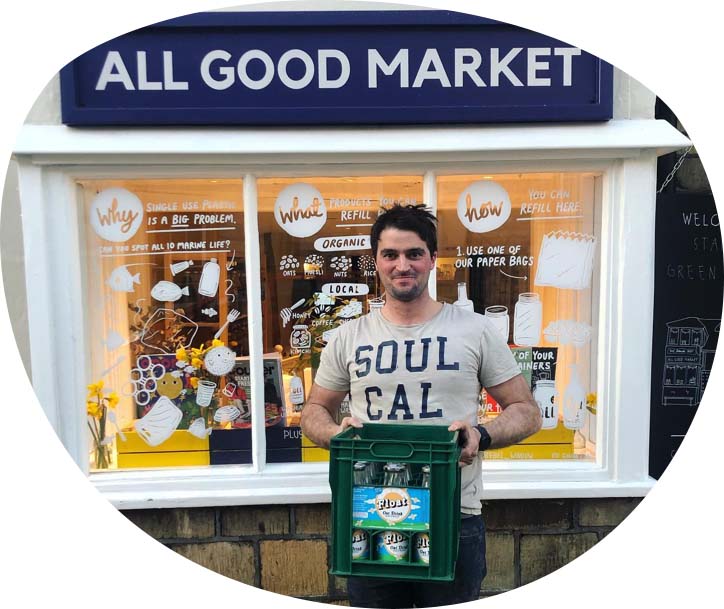 A picture of Jack, the Float Milk brewer, standing outside All Good Market with a crate of empty bottles to be washed and reused.